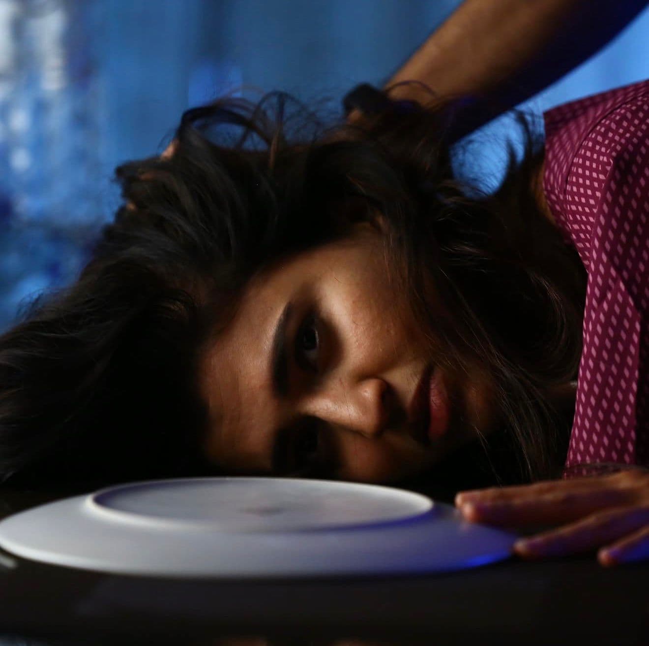 Close-up of an actress with her head tilted back, hair spread across the table surface