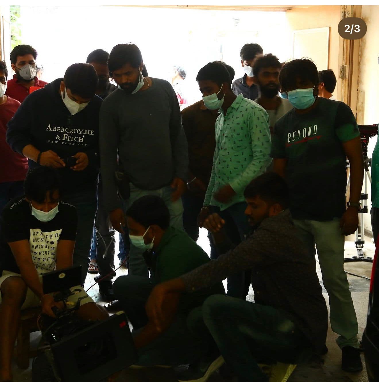 Crew crouched around a video monitor rig at the same daylight location