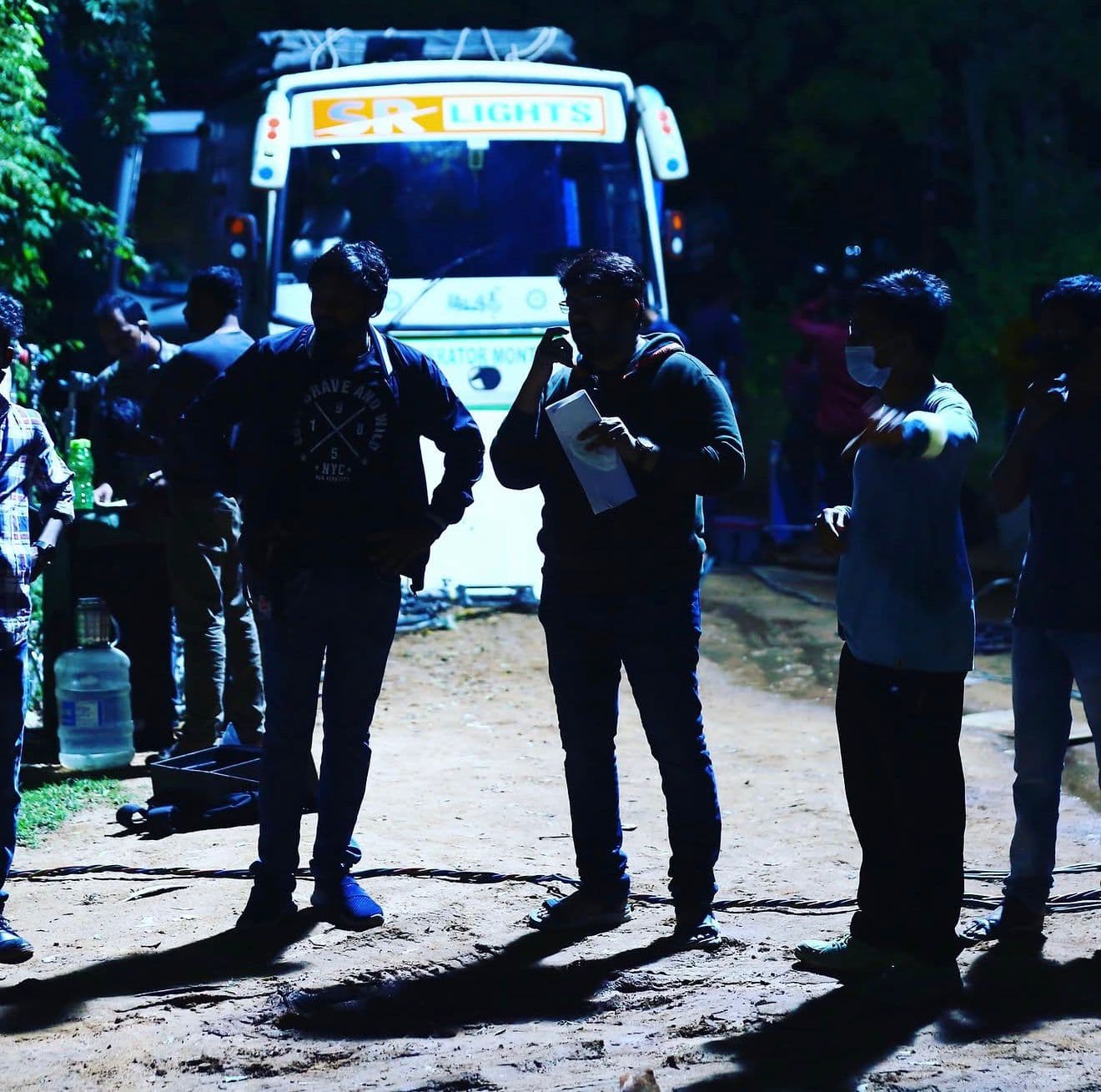 Crew members standing near a production truck at night
