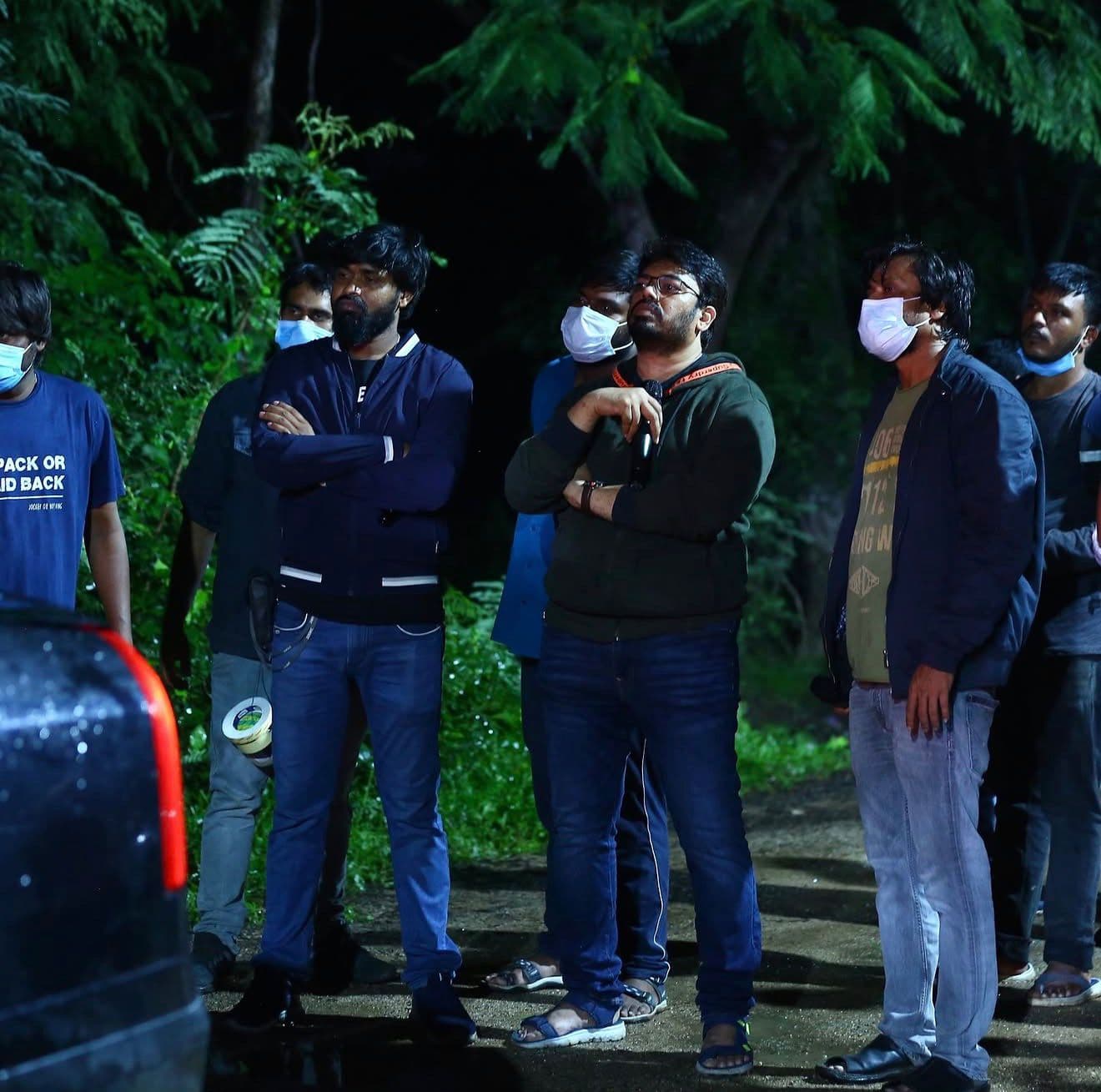 A crew group standing together at night in a wooded area