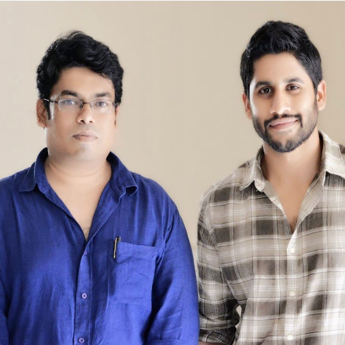 Two men posing for a portrait against a plain studio backdrop
