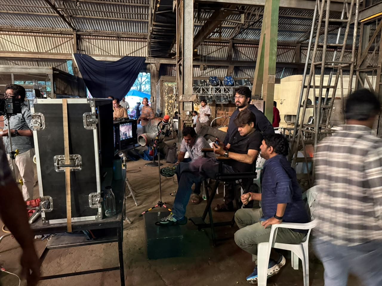 Wide shot of a film crew and equipment cases set up inside a warehouse-style studio