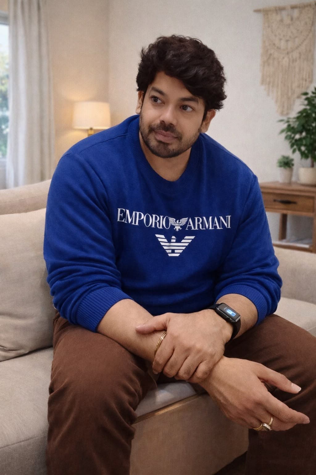 Arjun Prashanth seated on a couch at home, wearing a blue Emporio Armani sweatshirt
